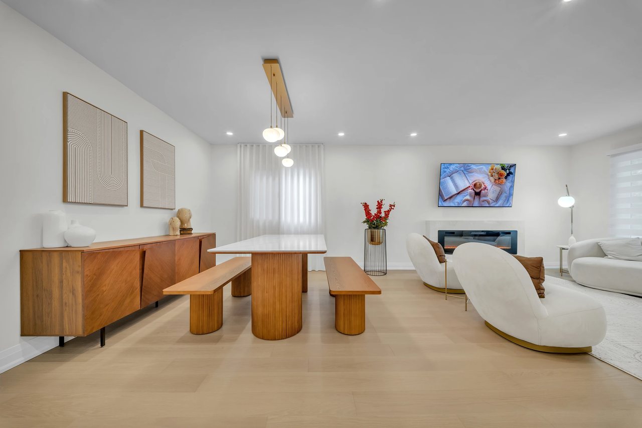 Bright living room with a white sofa, wood furniture, and an open kitchen.