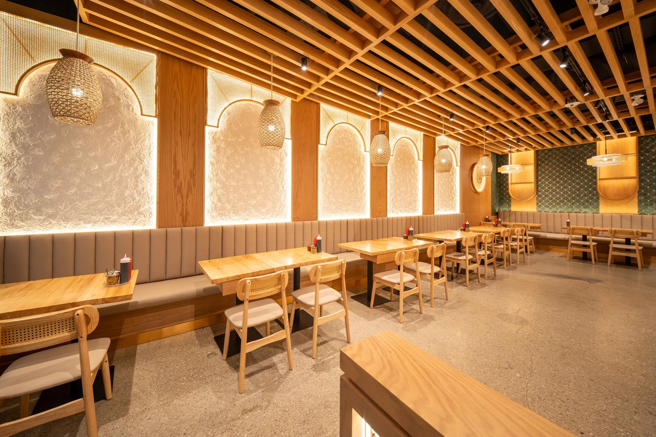 Restaurant dining room with wood ceiling slats, woven pendant lights, and arched wall details.