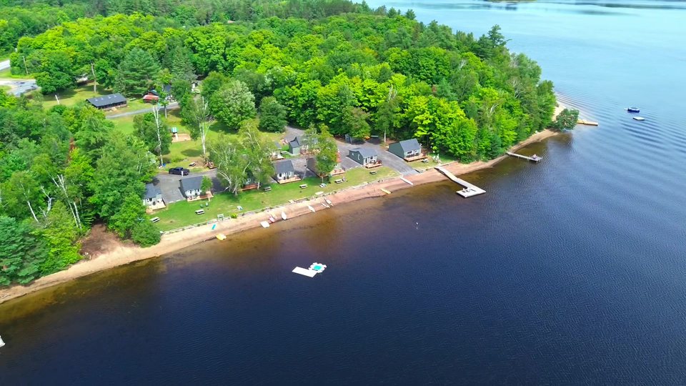 Aerial view of a wooded lakeside property and its shoreline, from a DENIS VISUAL film.